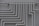 A series of parallel white pipes with multiple bends and joints is arranged on a light gray wall. The pipes display slight rust and wear in certain areas, indicating exposure to elements over time.