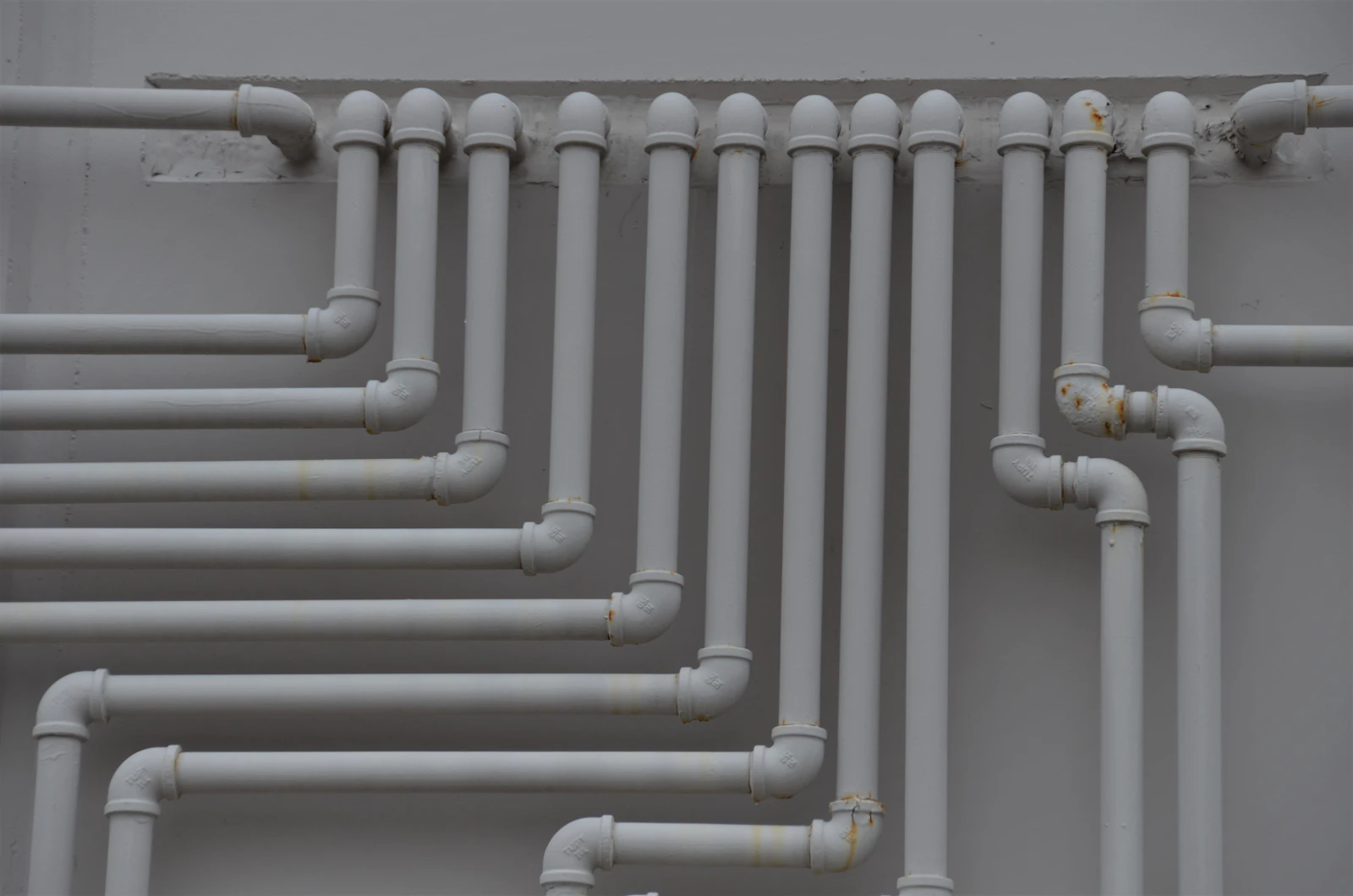 A close view of a bank of pipes running along a wall