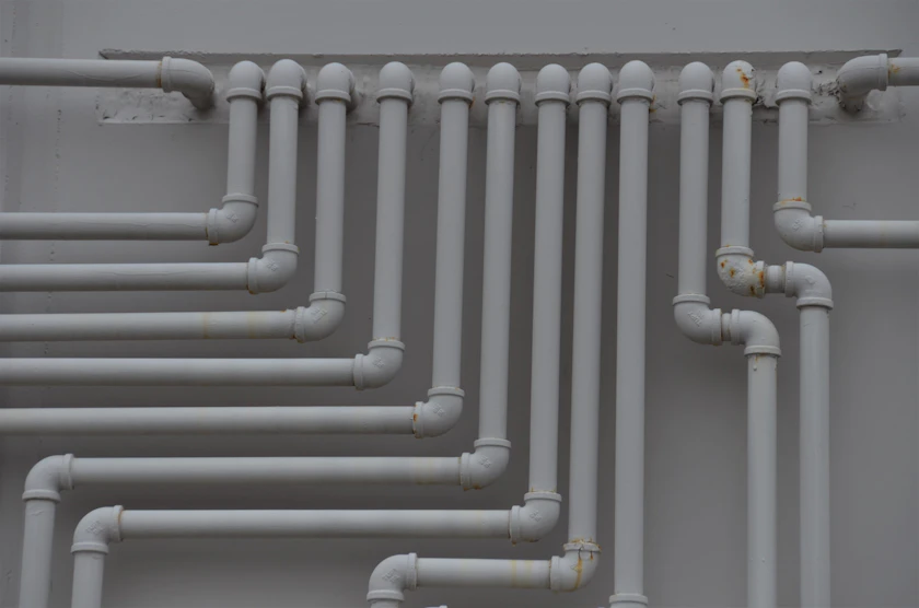 Rows of grey plastic pipework running in neat right angles across an industrial wall.