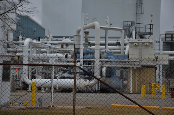 a factory with pipes and pipes behind a chain link fence