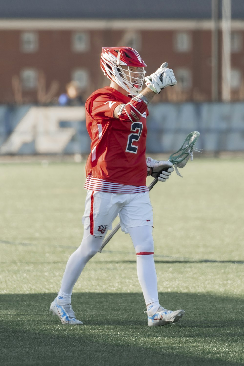 Un hombre con uniforme rojo sosteniendo una pelota de lacrosse