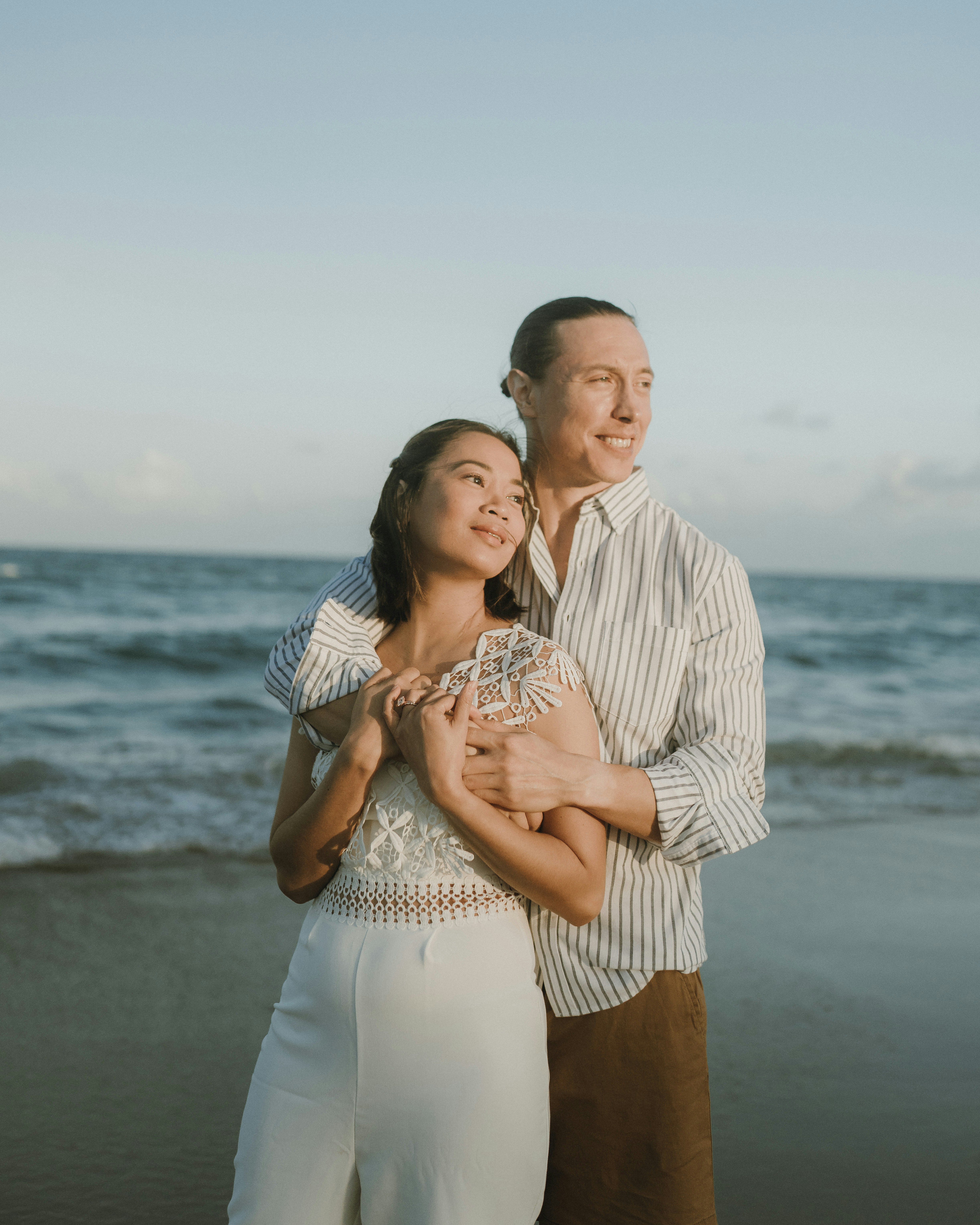 a man and woman standing on a beach next to the ocean