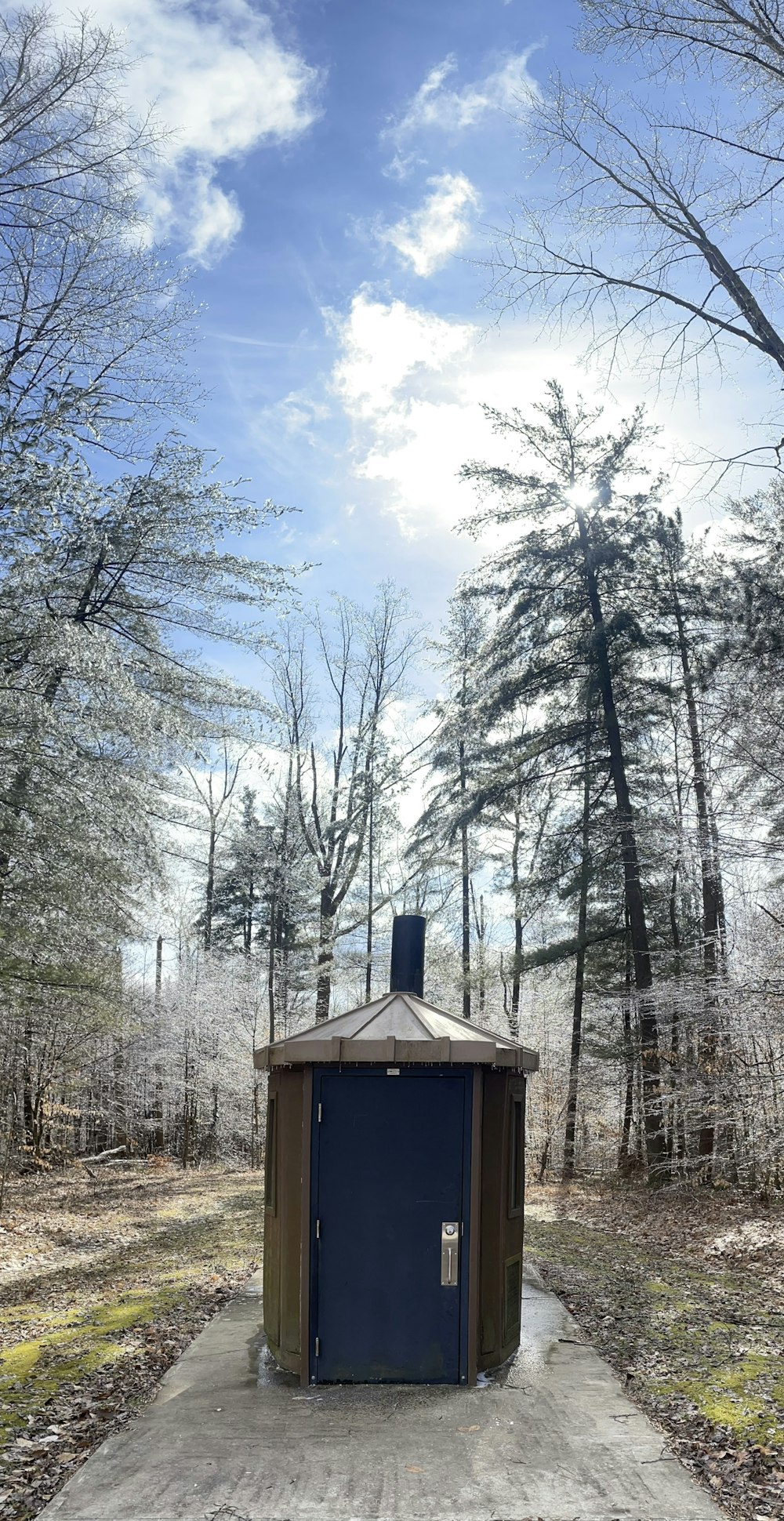 a small outhouse in the middle of a wooded area