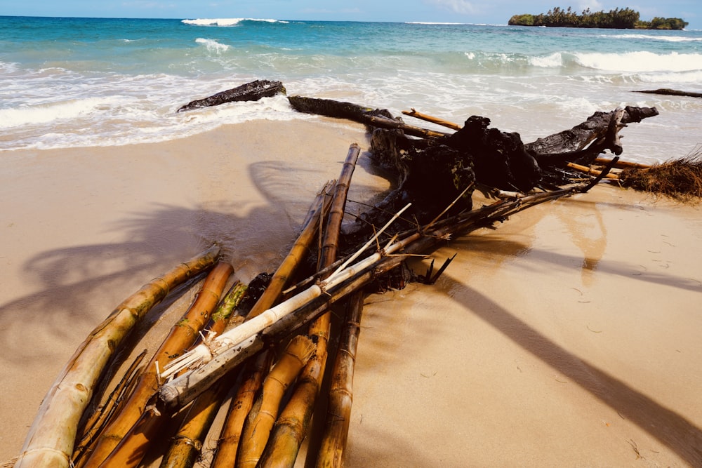 a pile of bamboo sitting on top of a sandy beach