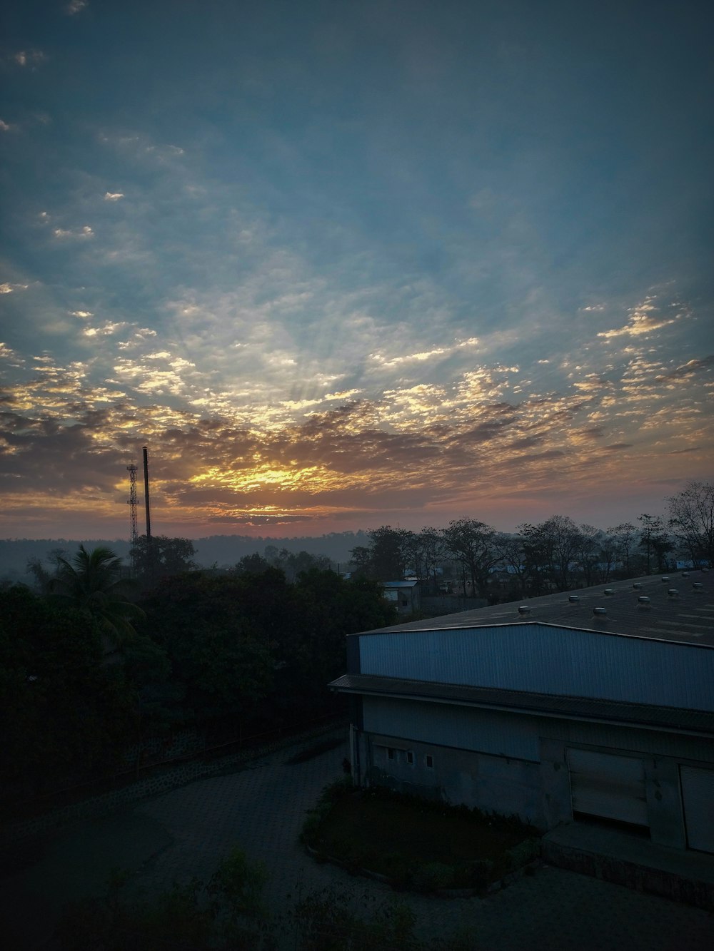 the sun is setting over a building and trees