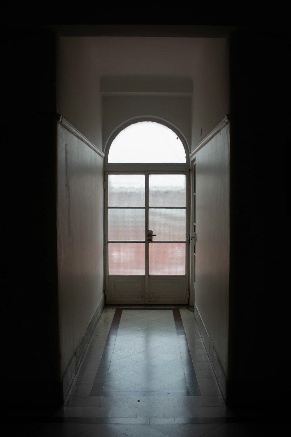 a dark hallway with a door and a window