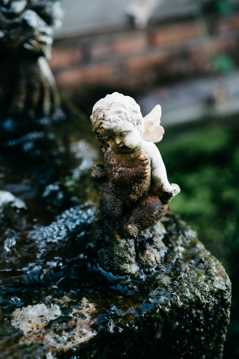 a statue of a little angel sitting on top of a rock