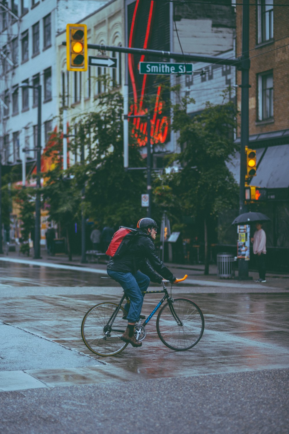 um homem andando de bicicleta por uma rua encharcada de chuva