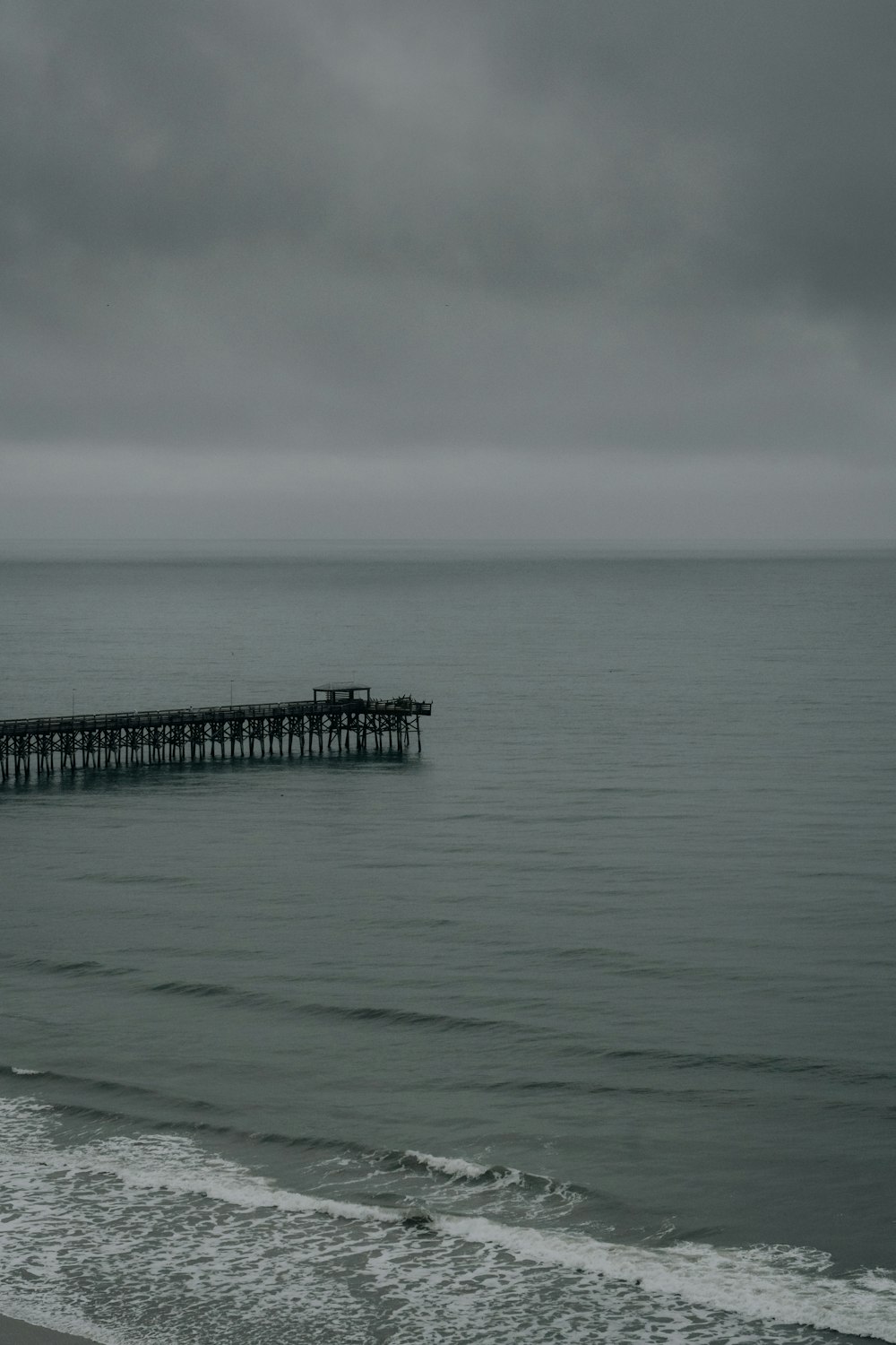 Una foto en blanco y negro de un muelle en el océano