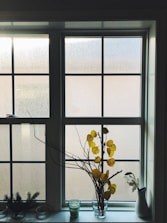 a vase of flowers sitting on a window sill