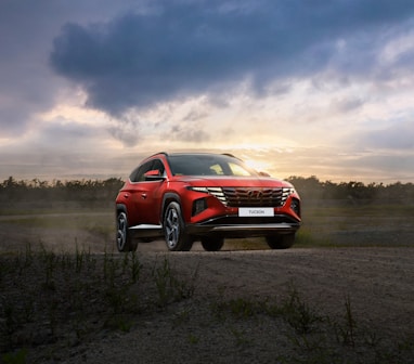 a red suv driving down a dirt road