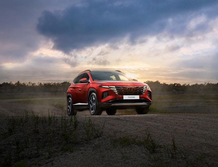 a red suv driving down a dirt road