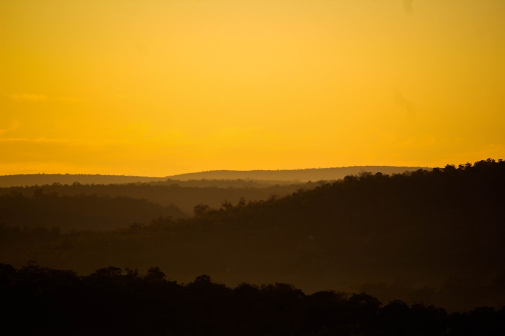 the sun is setting over the hills in the distance