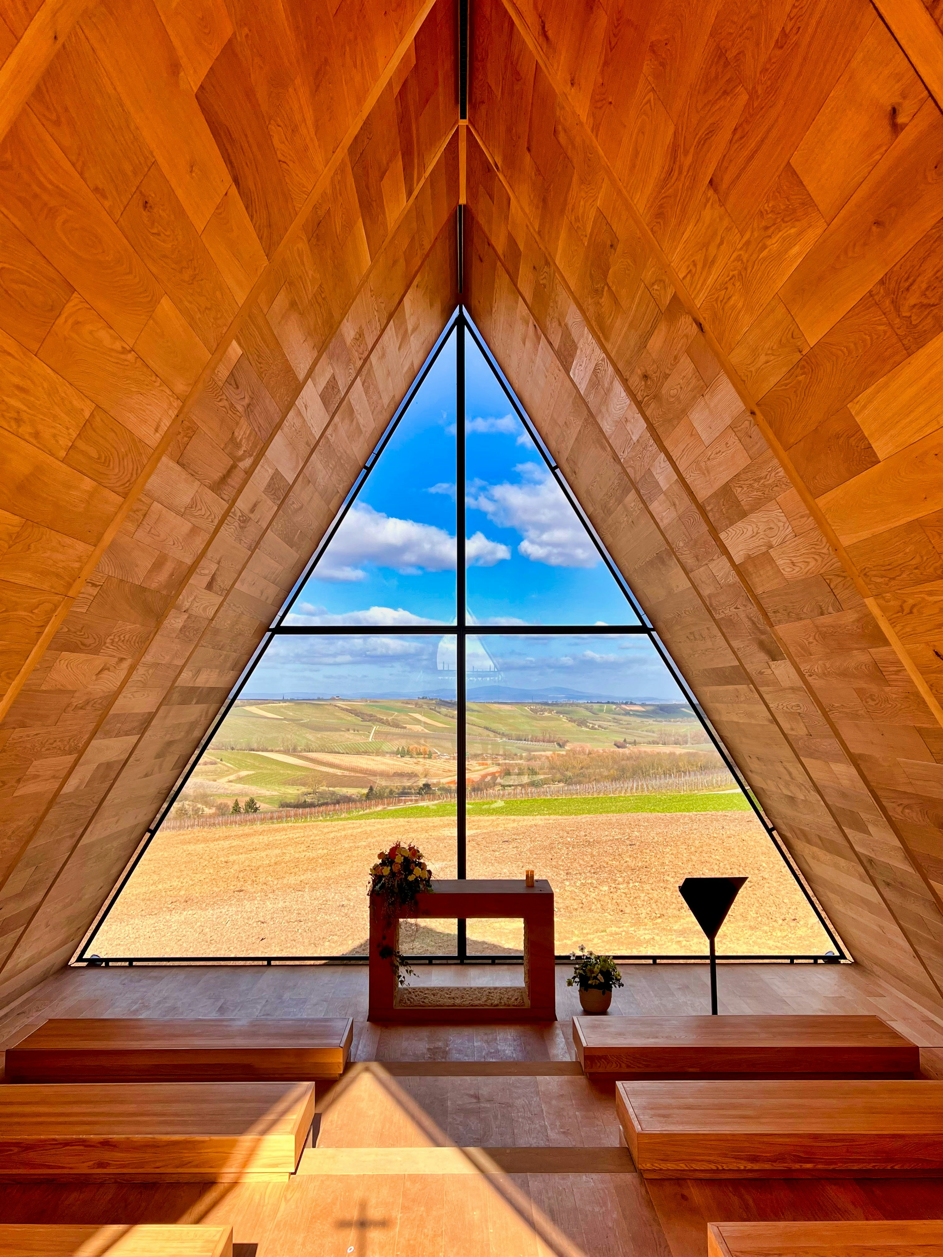 a wooden church with a large window and benches