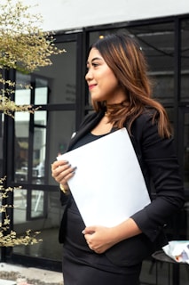 a woman in a black dress holding a white piece of paper