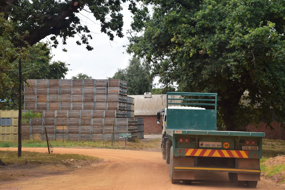 a green truck driving down a dirt road