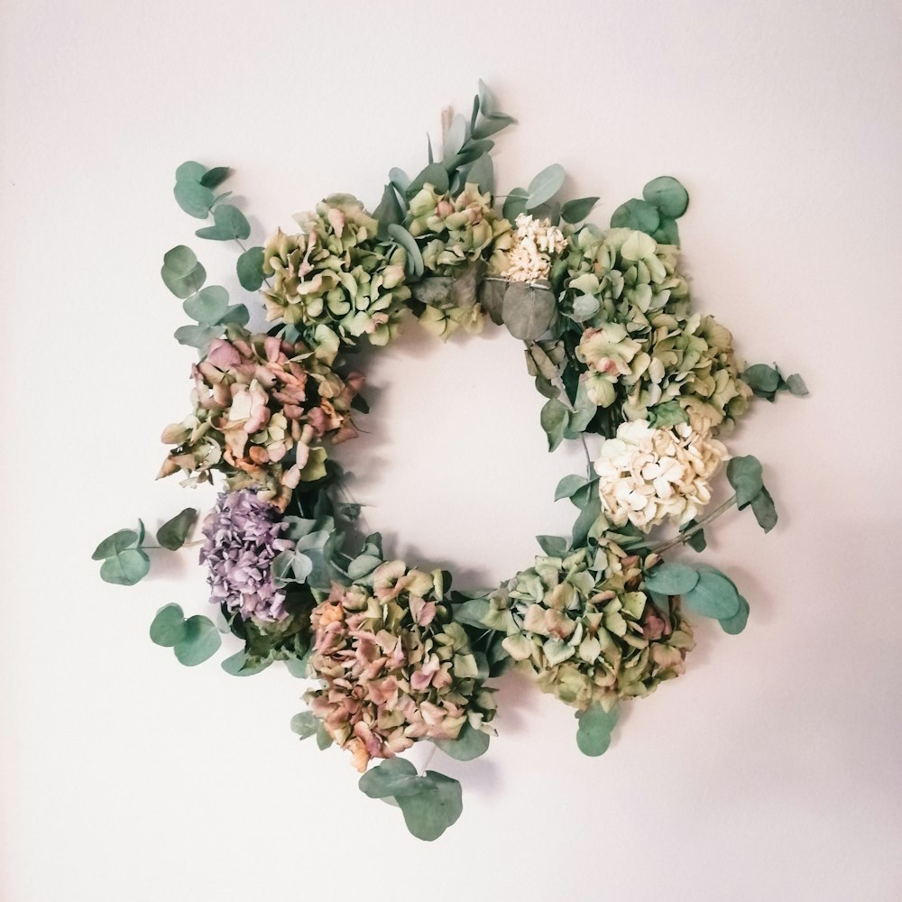a wreath of flowers and leaves on a white wall