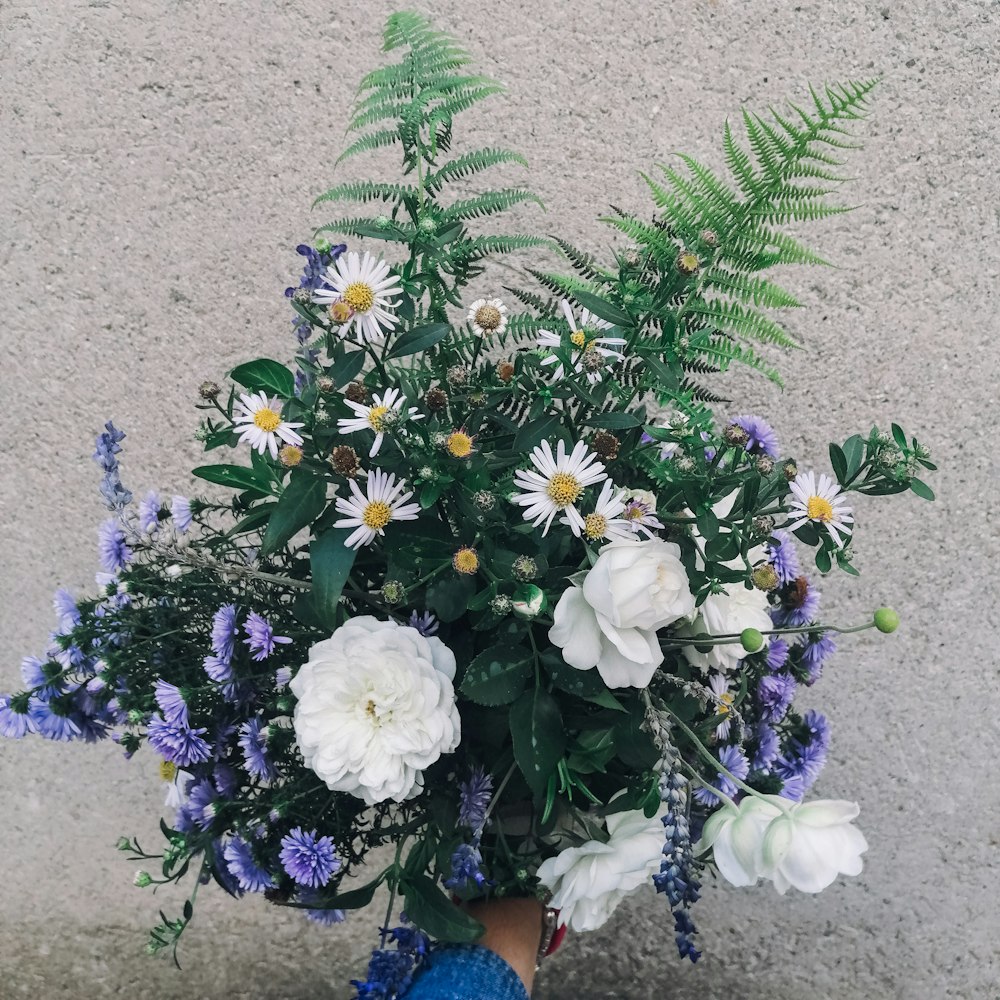 a person holding a bouquet of white and blue flowers