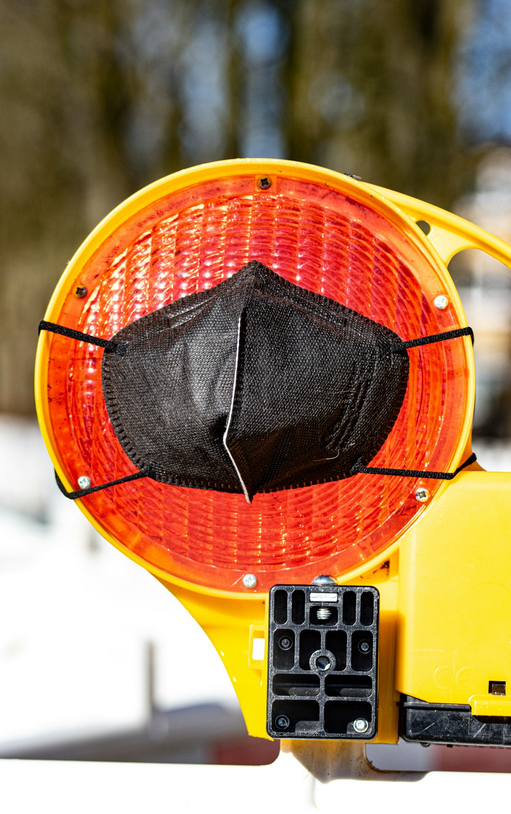 un semaforo giallo con una maschera facciale nera su di esso
