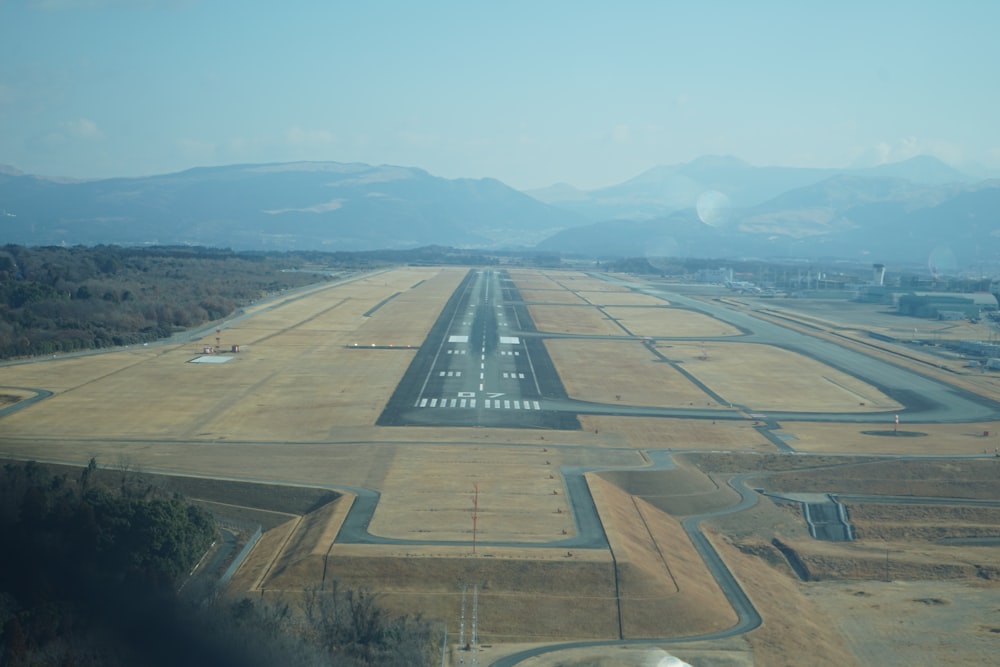 an aerial view of an airport runway with mountains in the background