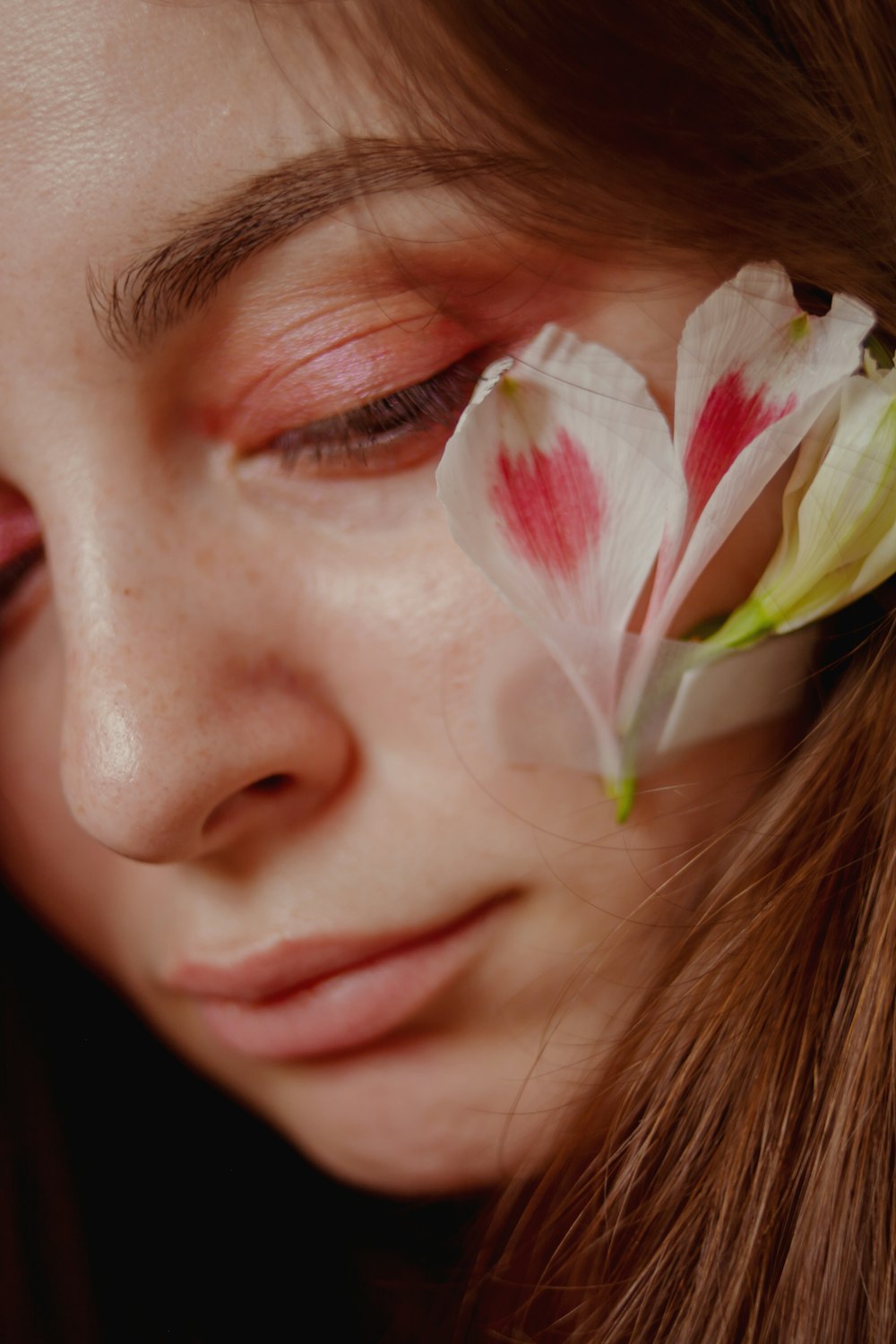 a close up of a woman with a flower in her eye