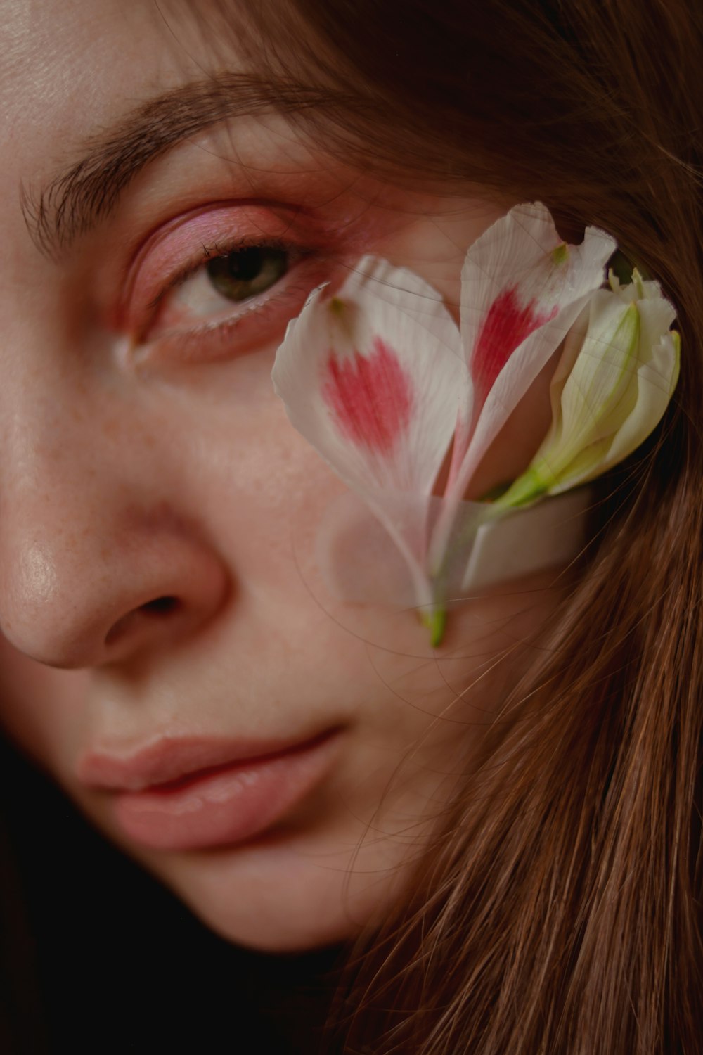 a close up of a woman with a flower in her eye