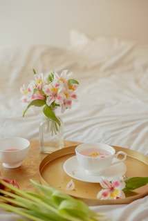 A delicate tea set surrounded by steaming cups of herbal infusions with petals floating on top.