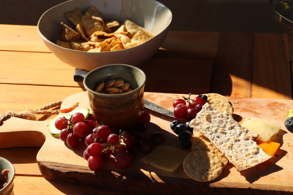 a wooden cutting board topped with grapes and crackers