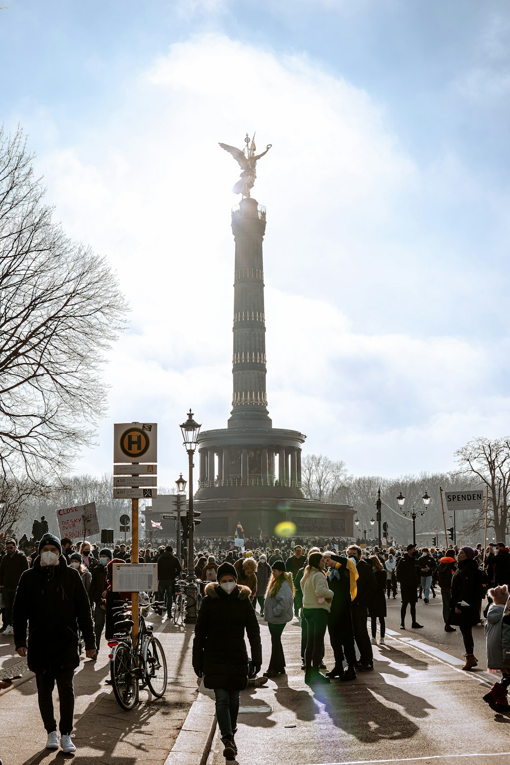 a crowd of people walking down a street next to a statue