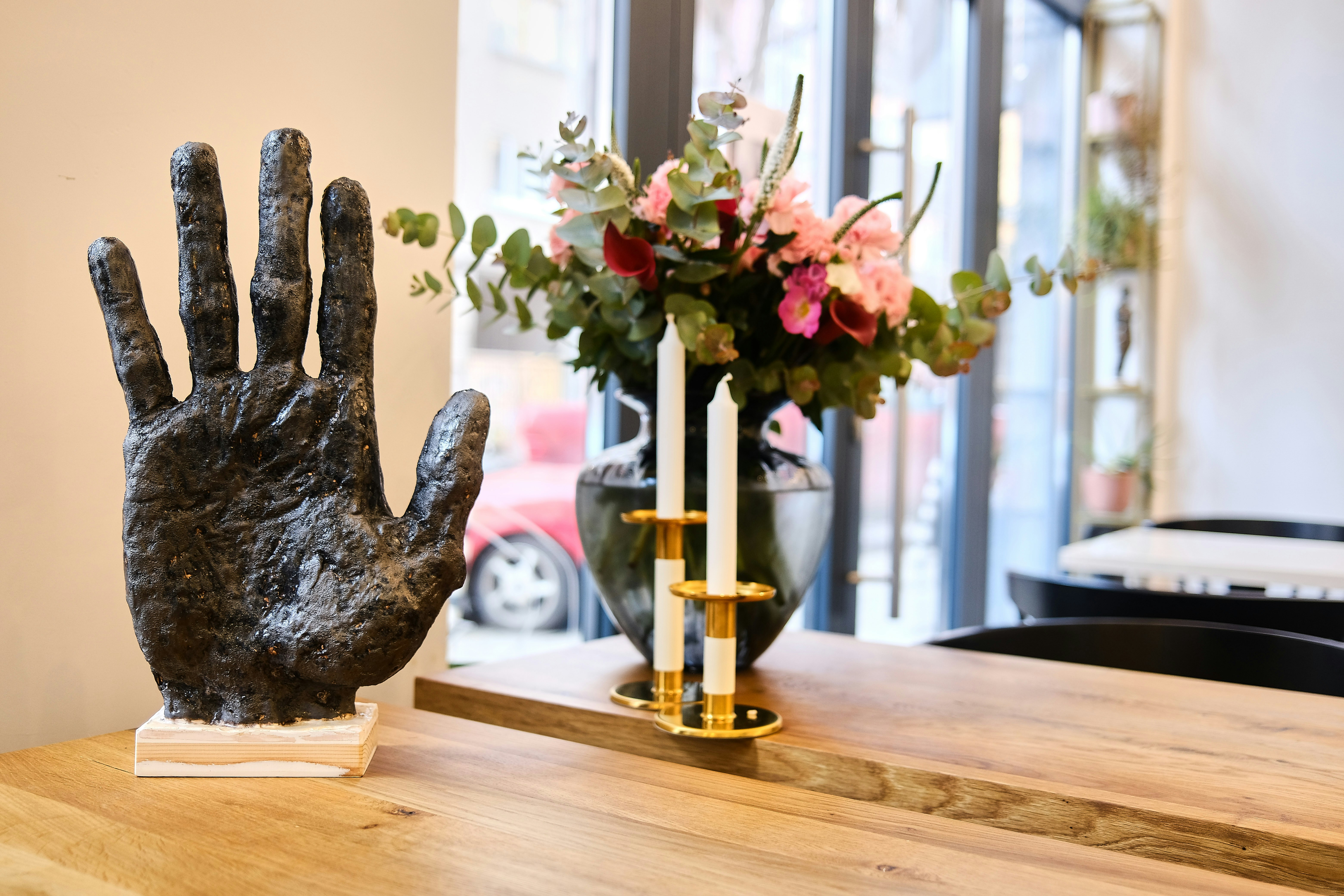 a statue of a hand on a table next to a vase of flowers