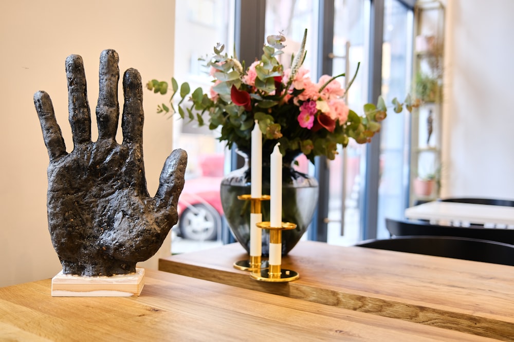 a statue of a hand on a table next to a vase of flowers