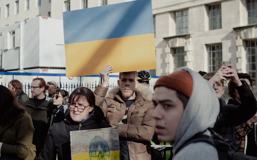 a group of people holding a flag and a sign