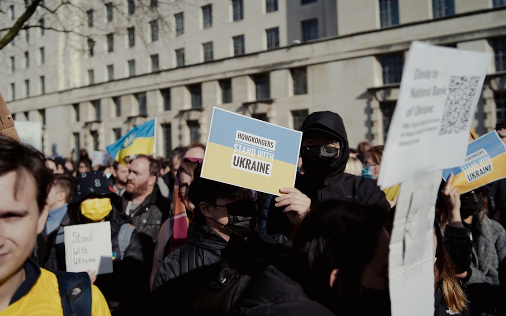 a crowd of people holding signs and wearing masks