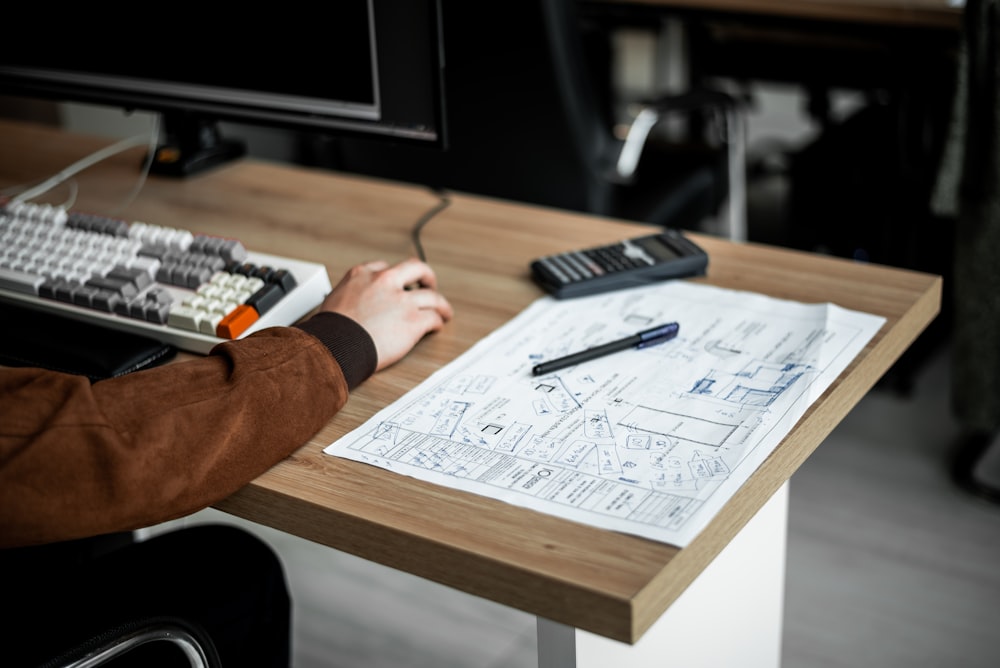 a person sitting at a desk with a pen and calculator