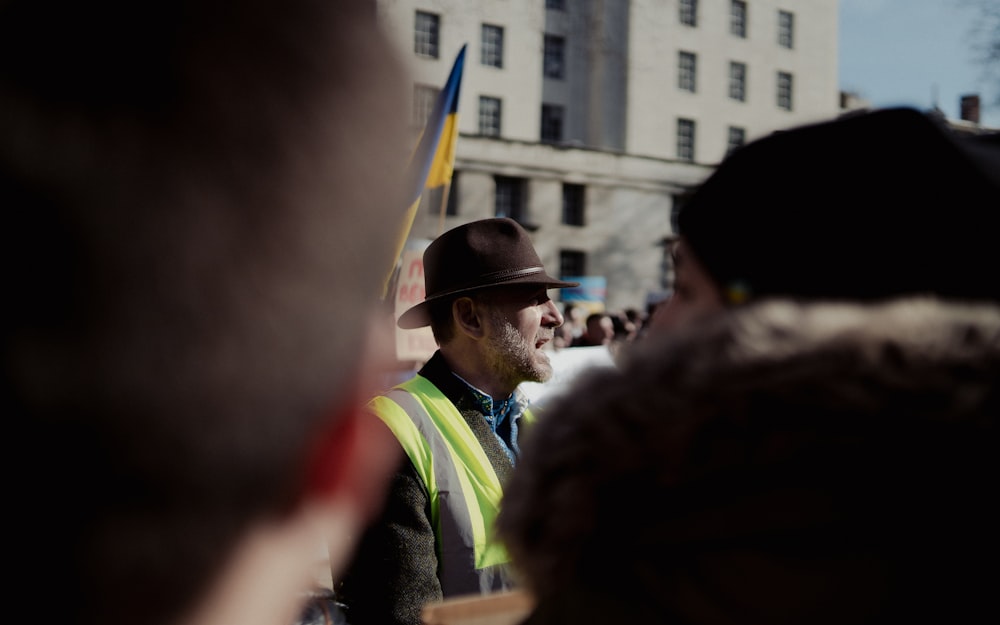 a man in a hat and vest standing in front of a crowd