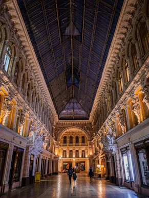 two people are walking through a large building