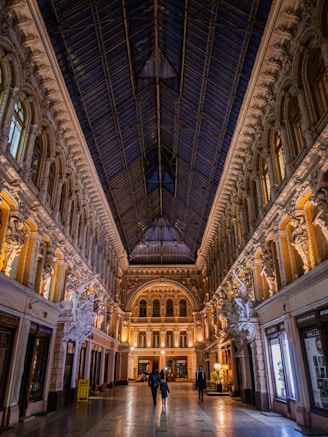 two people are walking through a large building