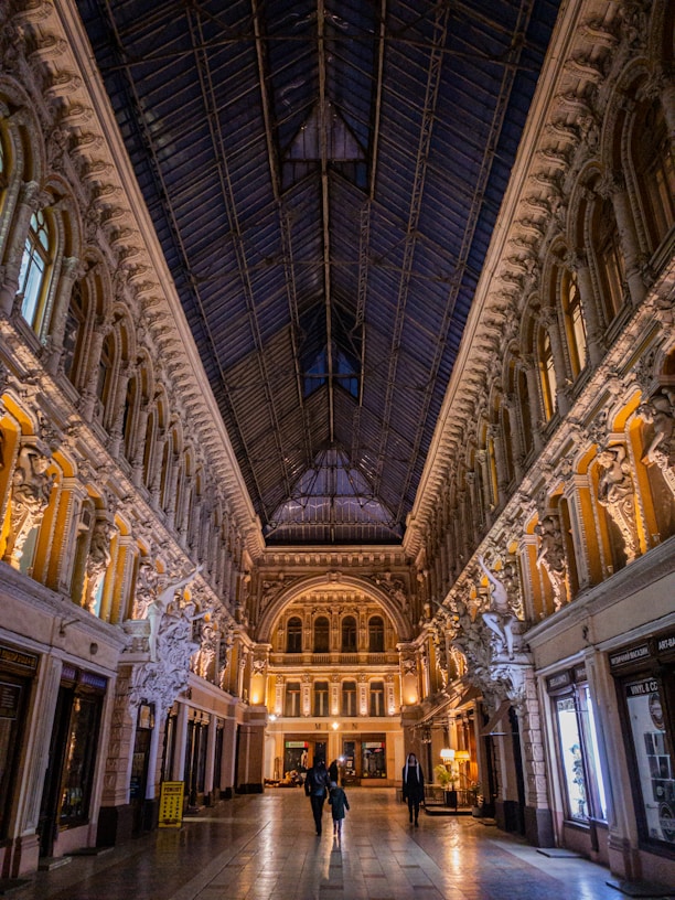 two people are walking through a large building