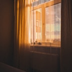 the sun is shining through the curtains of a window