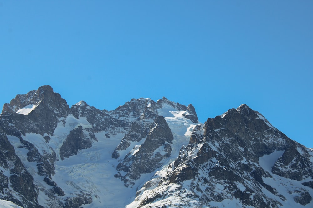 a snow covered mountain range under a blue sky