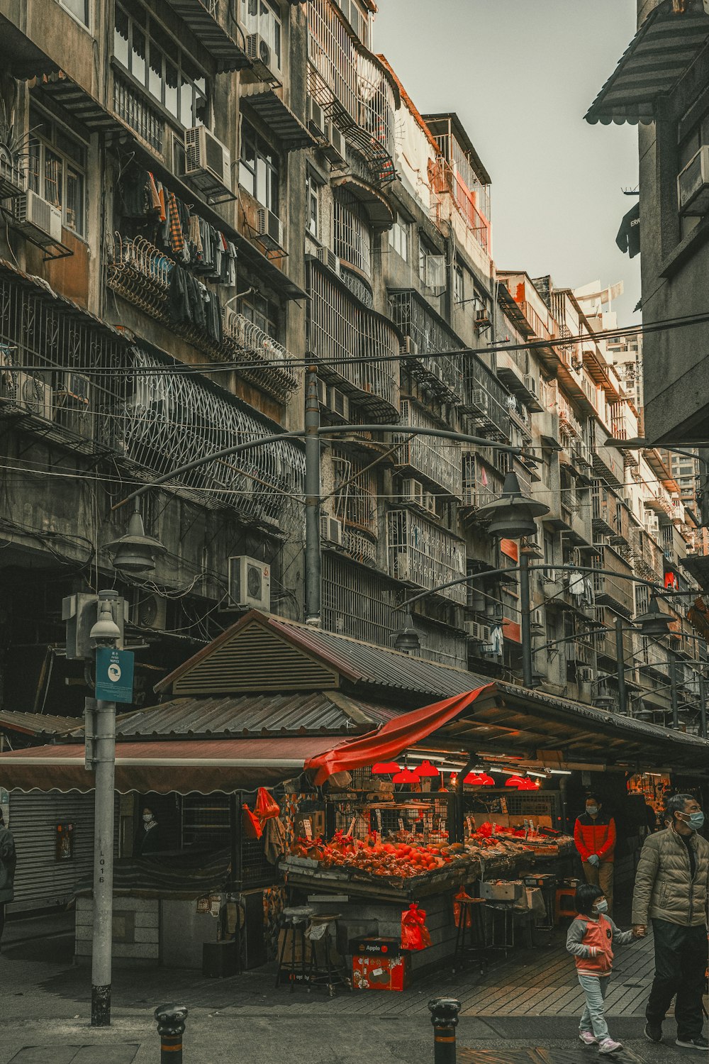 a group of people walking down a street next to tall buildings