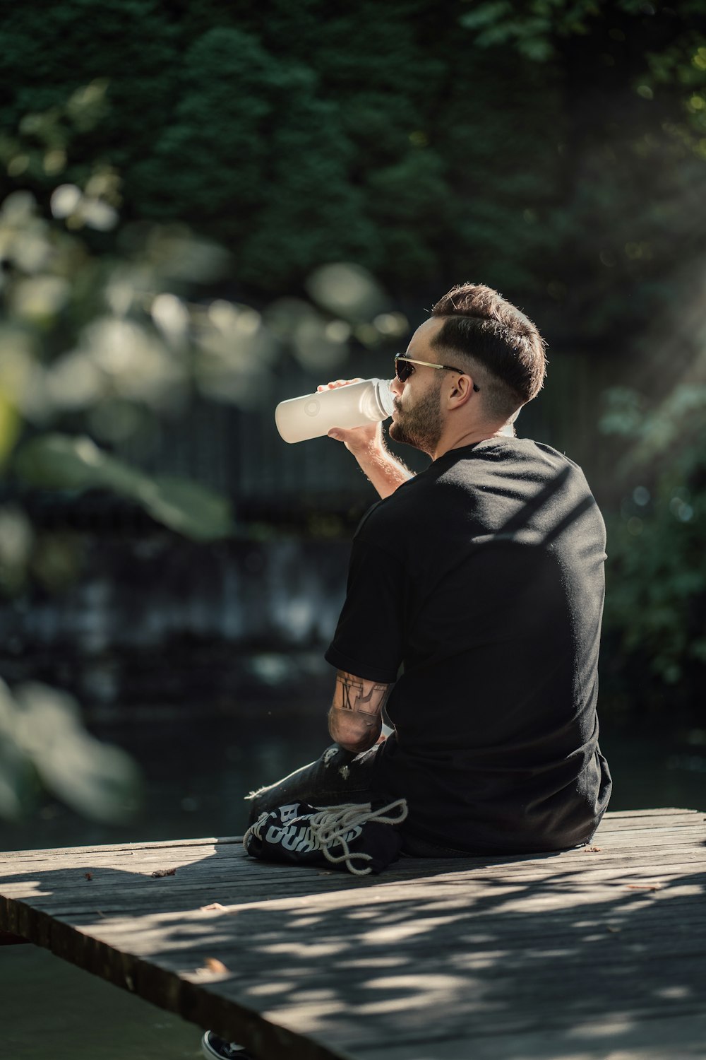 a man sitting on a dock drinking a bottle of water