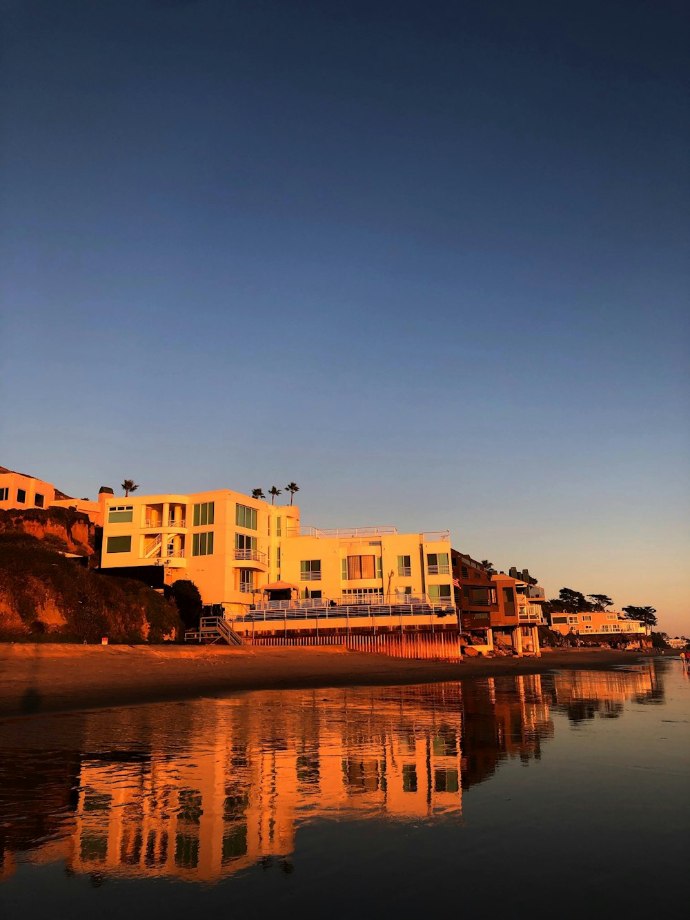 a large building sitting on top of a beach next to a body of water