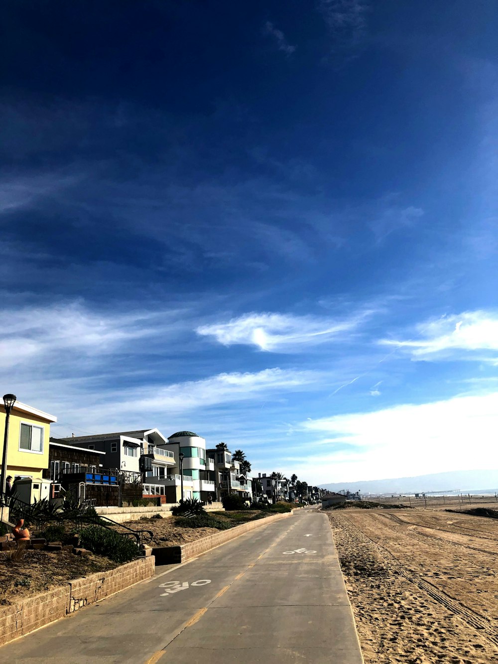 a long empty road with houses in the background