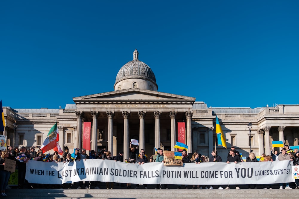 a group of people holding a banner in front of a building