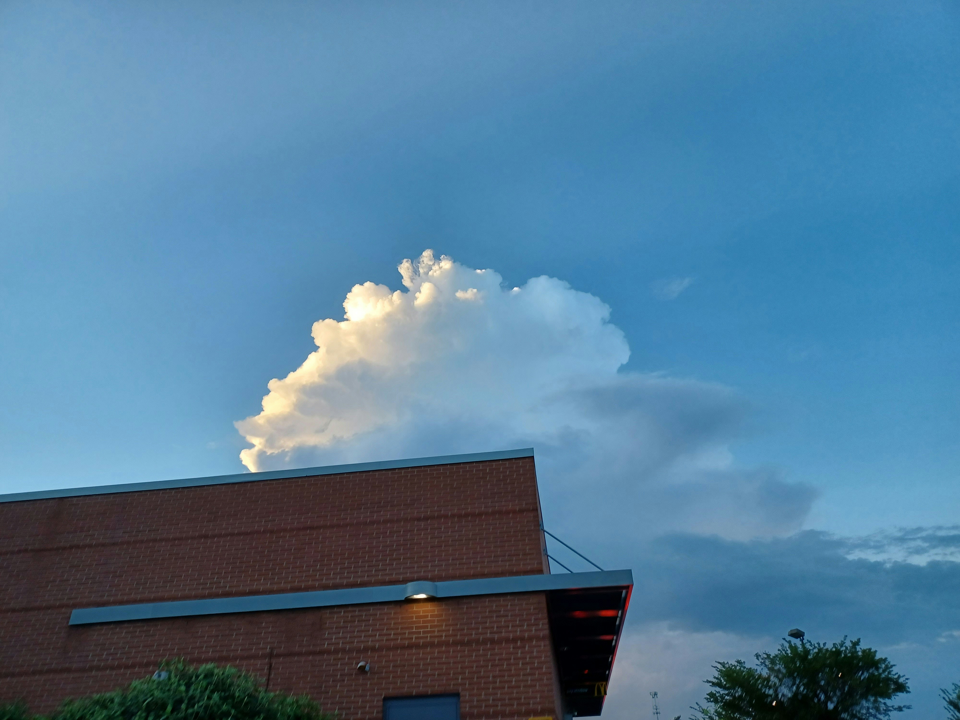 a large cloud looms over a brick building