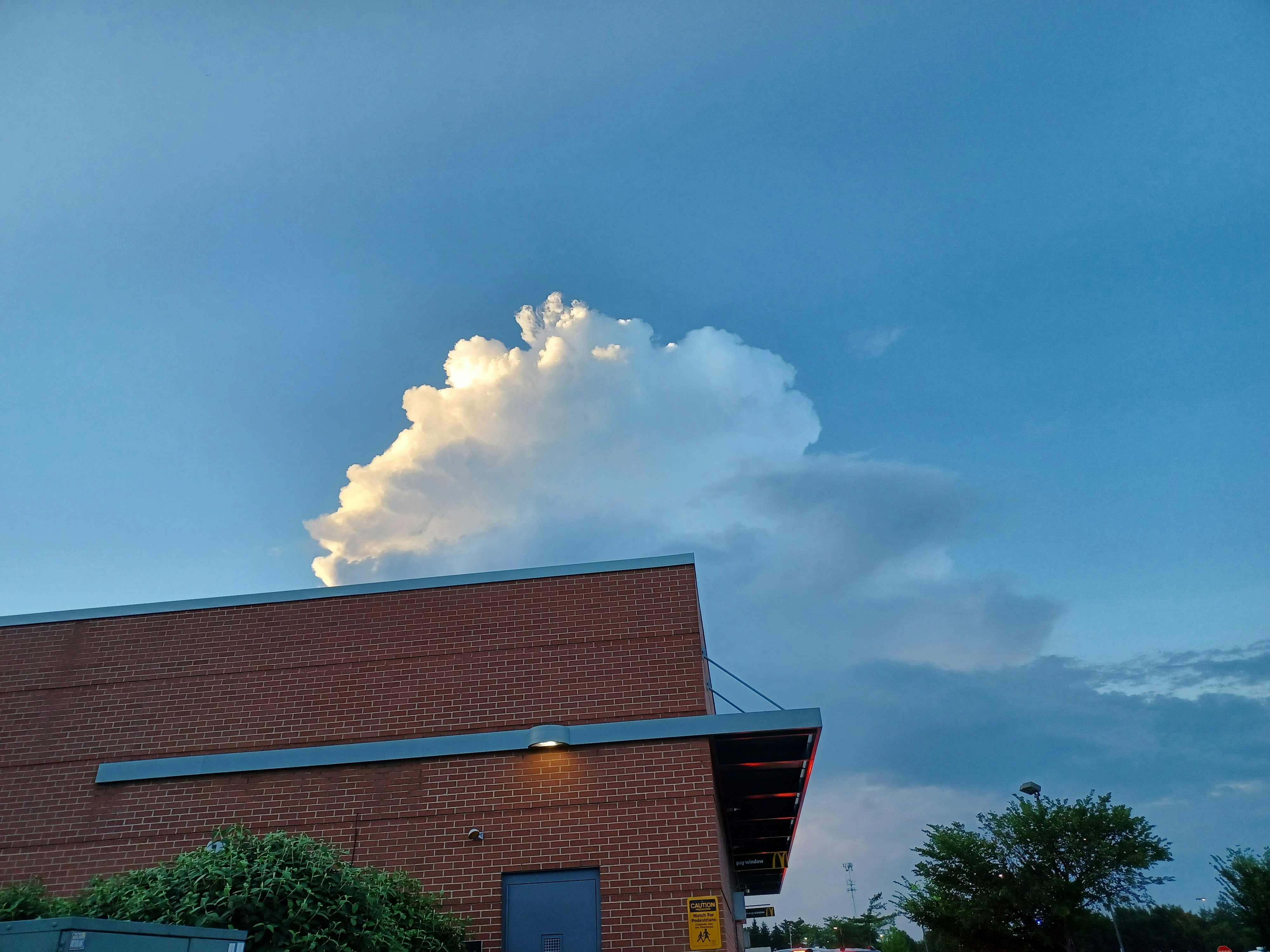 a large cloud looms over a brick building