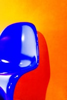 A vibrant, colorful chair with a unique design set against a minimalist backdrop.