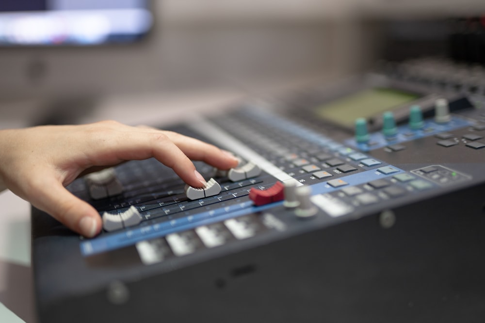 a person pressing buttons on a sound mixing console