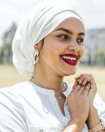 A fashionable woman showcasing her accessories while smiling in a bright, outdoor environment.
